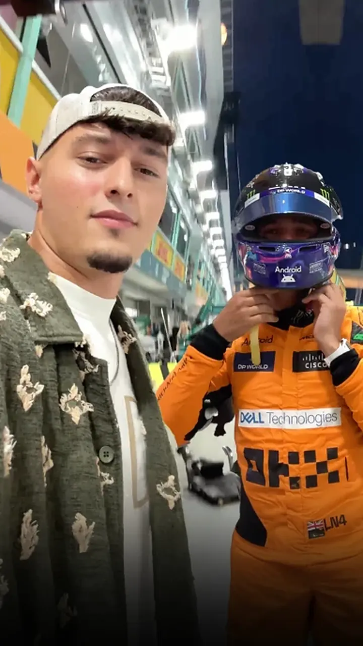 Nikolai Savic with Lando Norris in his helmet in the McLaren garage
